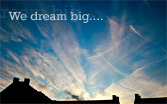 whispy clouds on a blue sky with the text We dream big...