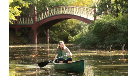 A person paddles a canoe in the Crim Dell pond