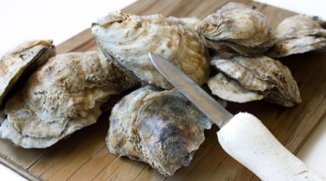 Oysters on a cutting board with a knife