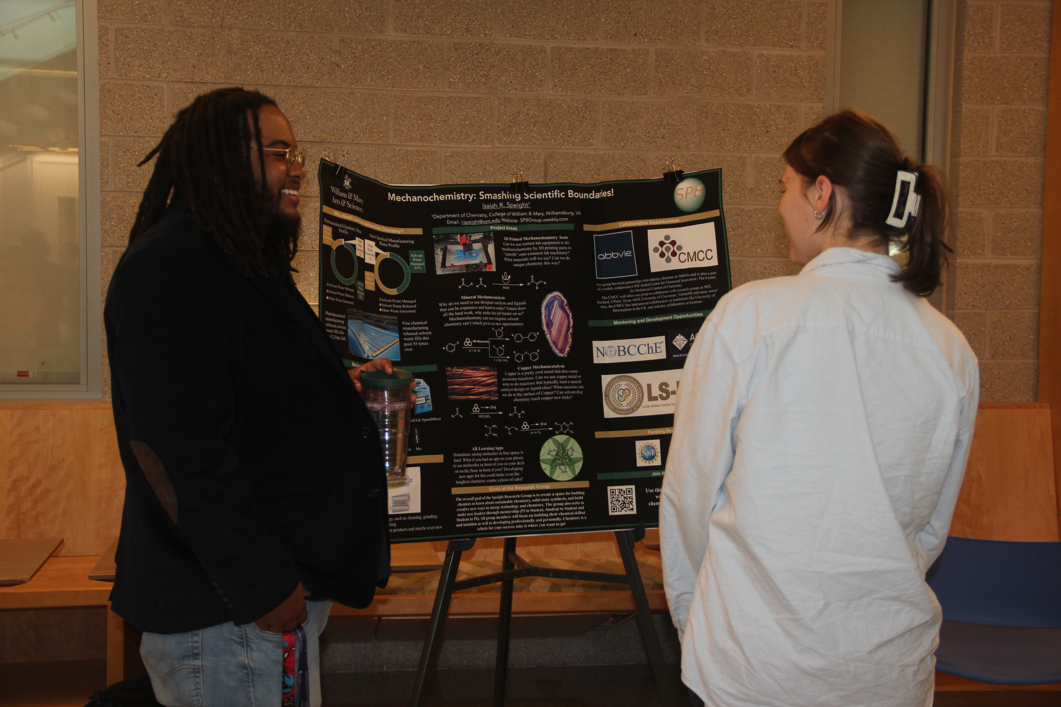 Professor Speight speaks with a student at a research fair.