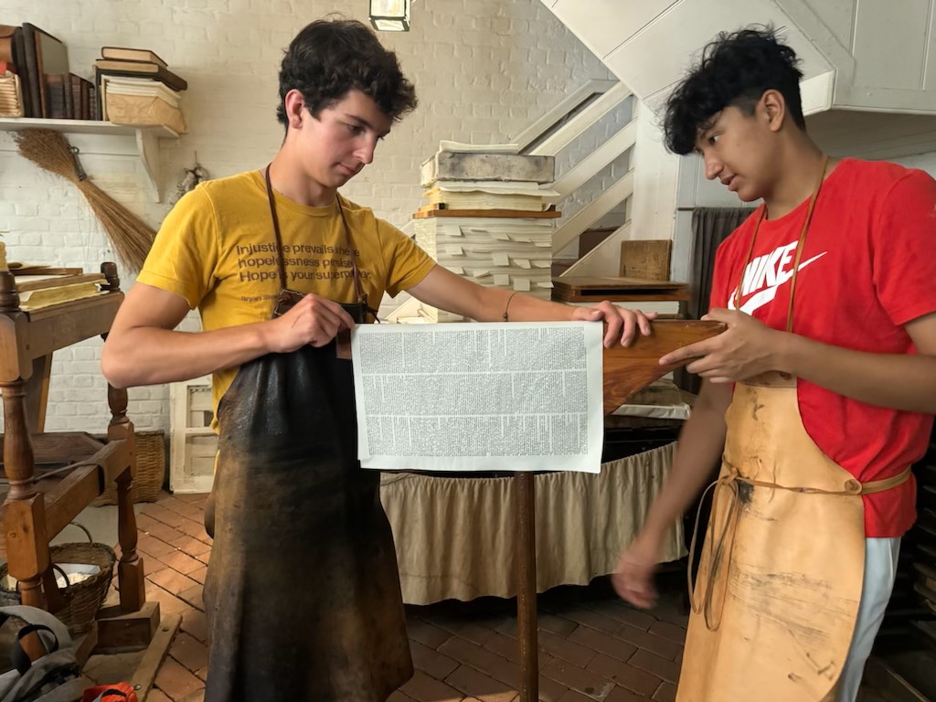 Students investigate English and colonial identities at the Colonial Williamsburg Printing Office by pressing the supplement to the September 2nd, 1773 Virginia Gazette