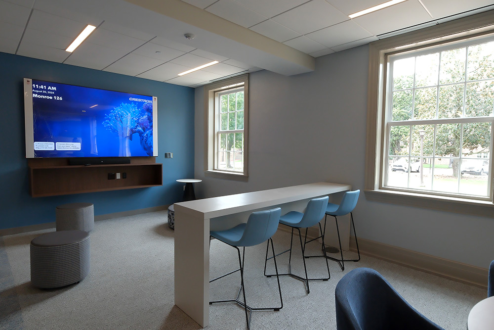 Lounge area with large windows and seating areas and a large mounted television