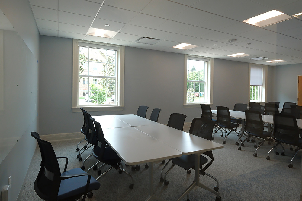 Large room with windows, whiteboard and re-configurable work tables and chairs