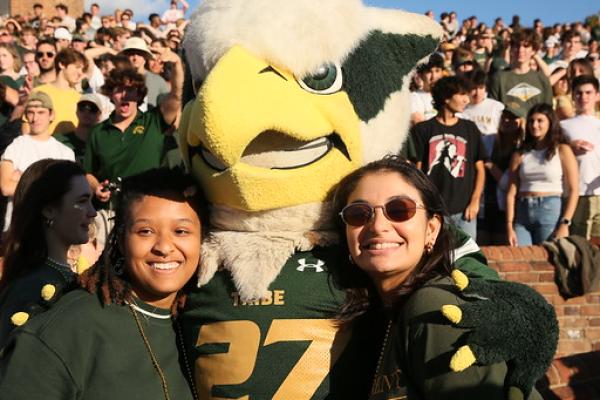 The William & Mary mascot poses for a photo with one person in each arm.