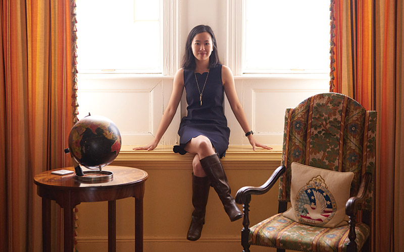 Student seated cross-legged in a confident pose on a window seat in front of a window in the Reves Center.