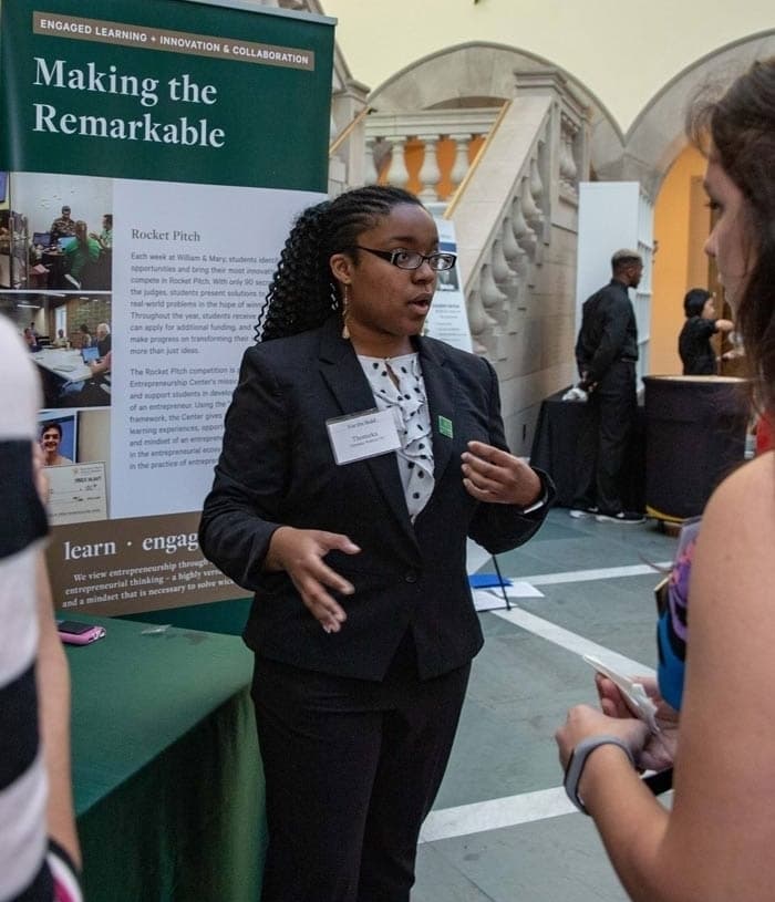 Person presenting in front of a display with the words Making the Remarkable