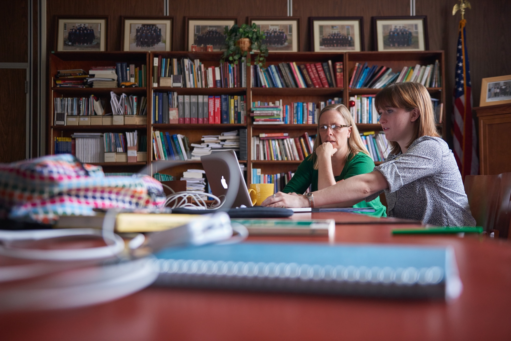 A student and professor seated in a library at a table