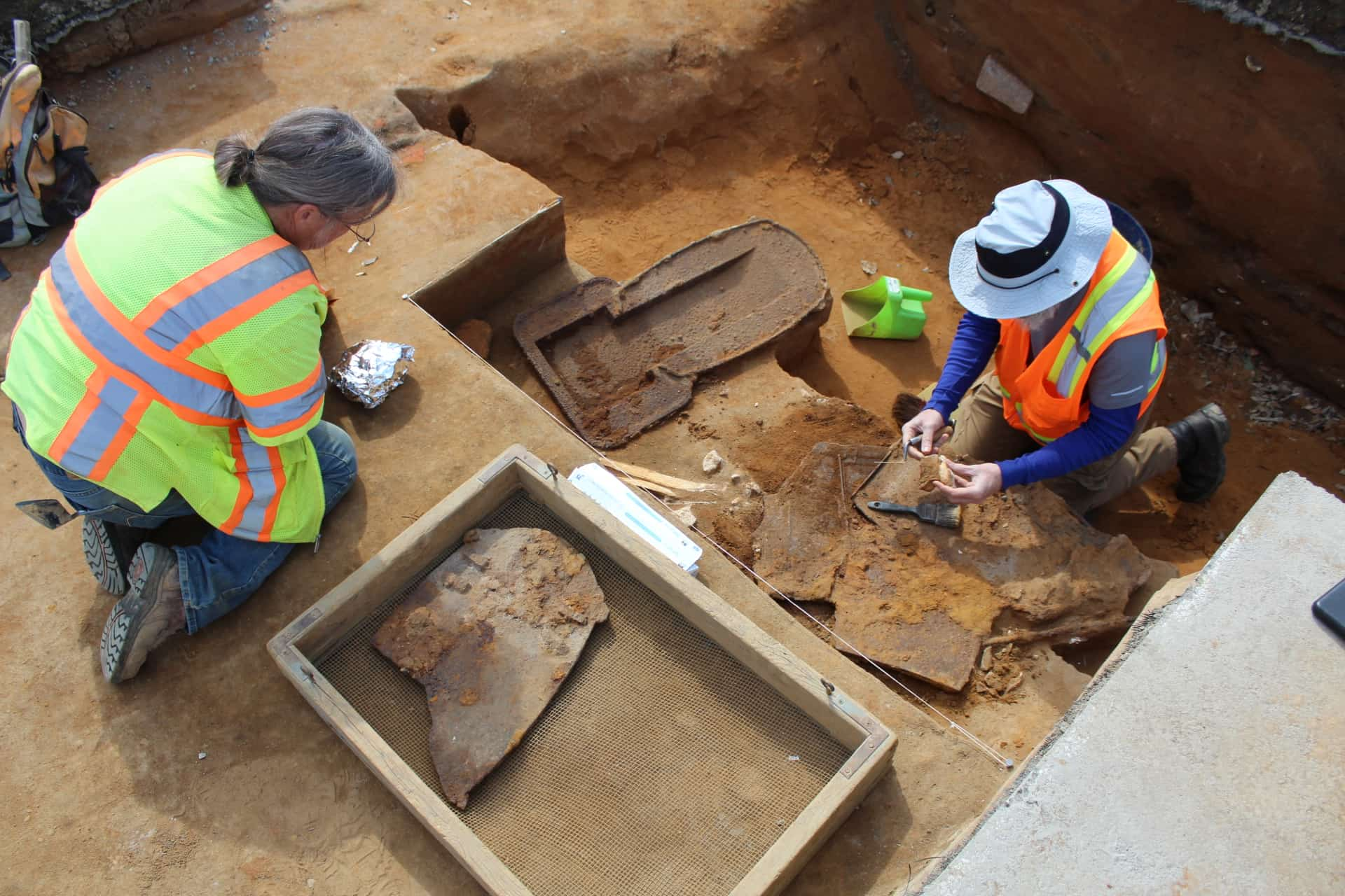 Field technicians carefully uncover cast iron pieces of an oven from underneath a parking lot at VIMS.